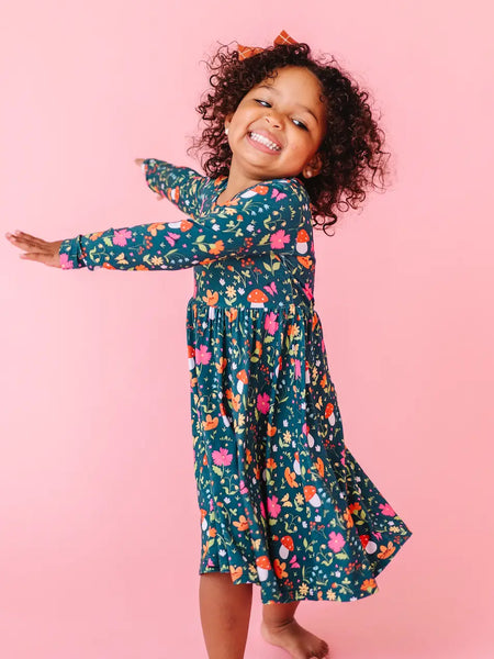 Child wearing a floral dress against a pink background