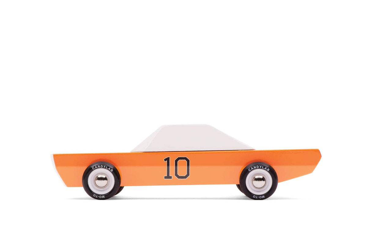 A wooden race car toy with an orange body, white roof, black racing stripes, and the number 10 on the side, shown against a plain off-white background.