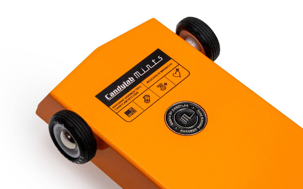A wooden race car toy with an orange body that has 'candylab mints' branding on a white background