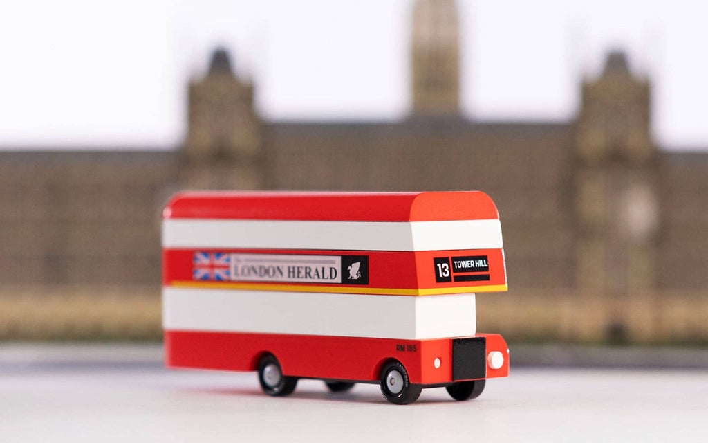 Toy double decker london herald bus against a city background