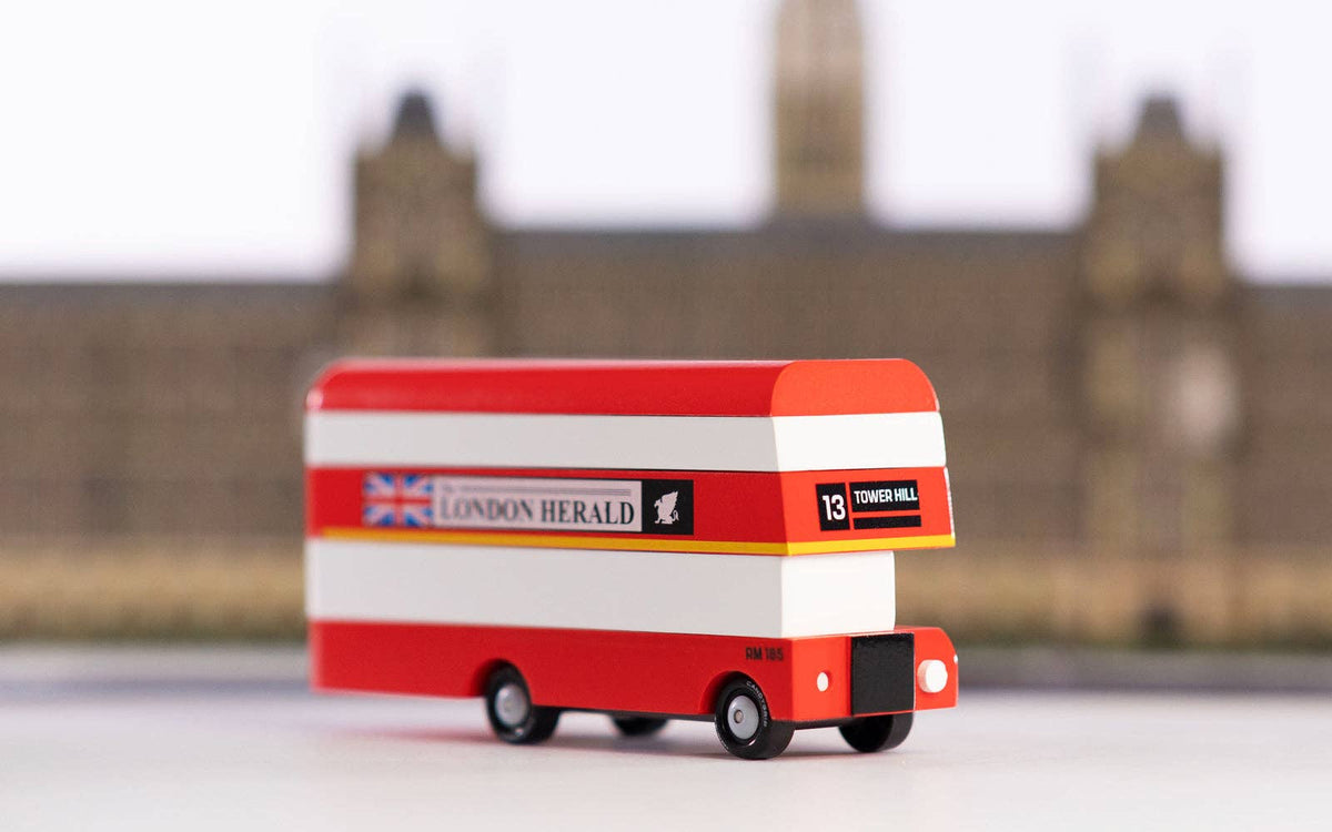 Toy double decker london herald bus against a city background