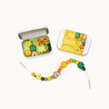 Colorful bead kit with open tin and string on a white background