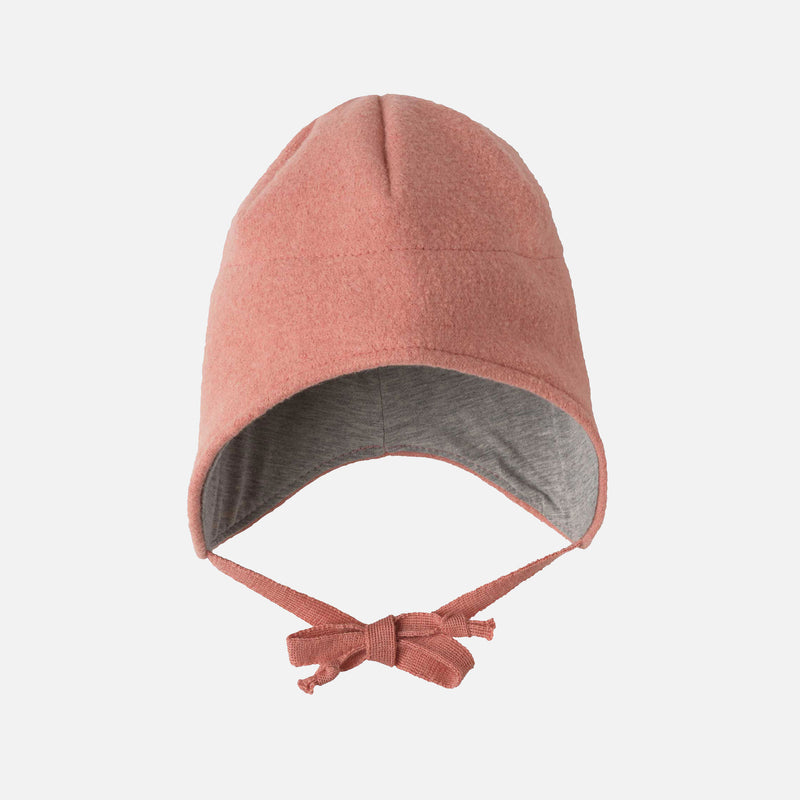 Pink baby bonnet with a bow on a white background
