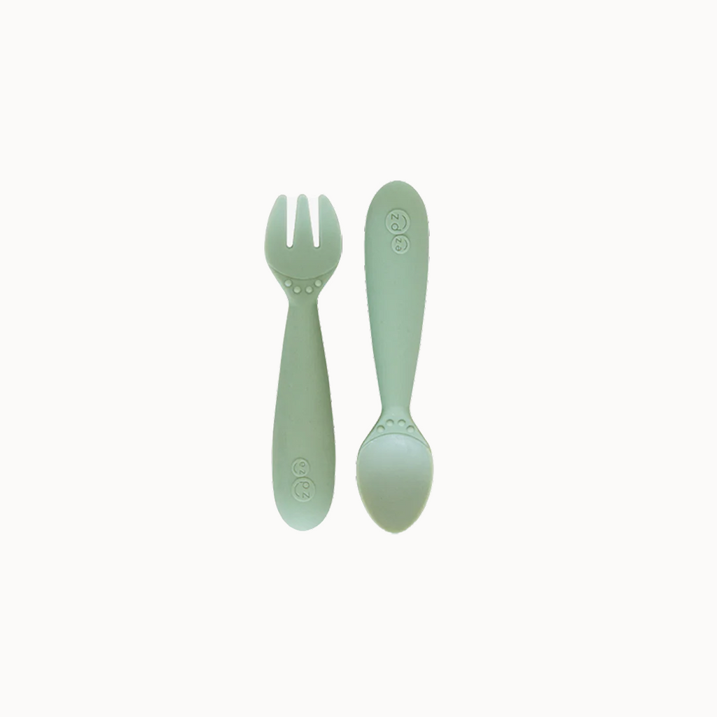 Packaged mini utensils consisting of a fork and spoon designed for toddlers, with a green color and sensory features.