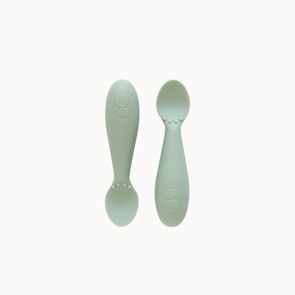 Two green silicone spoons designed for babies, with wide handles and narrow bowls.
