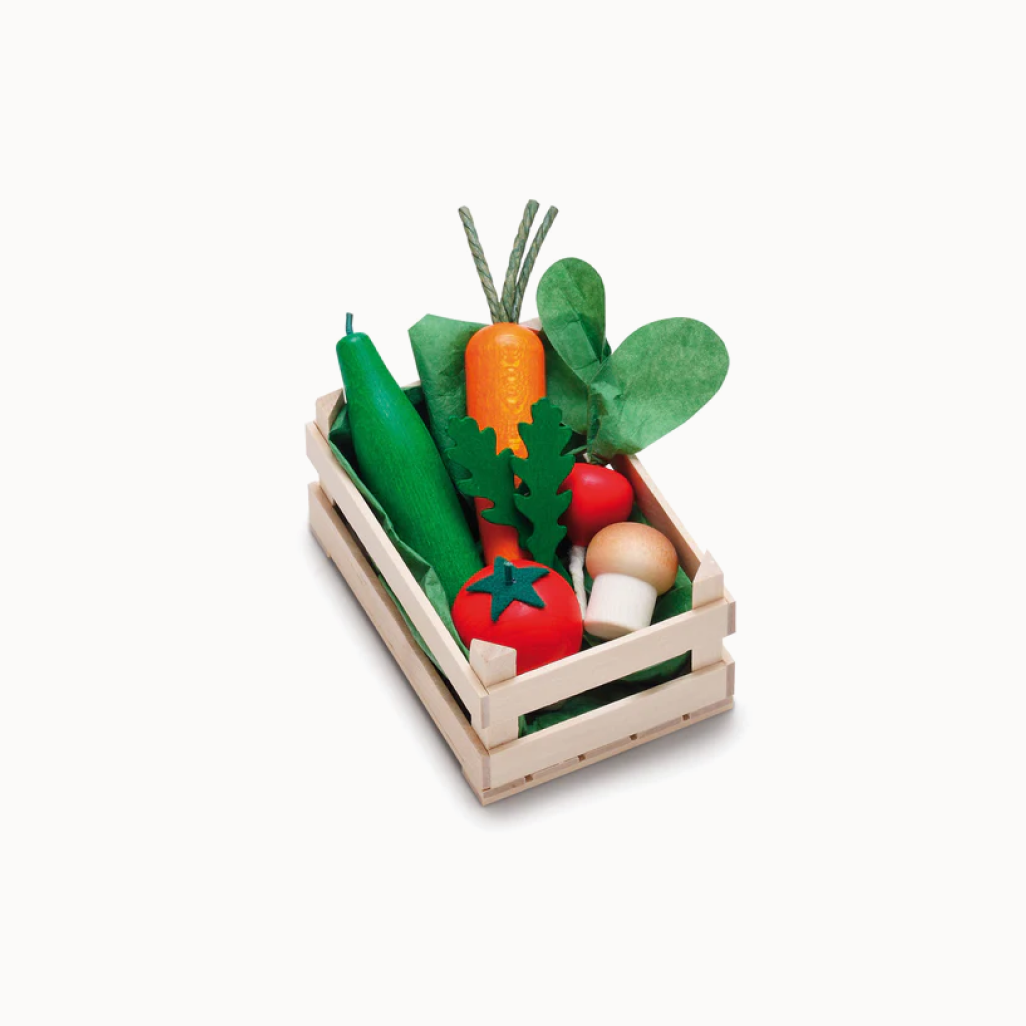 Set of toy vegetables in a wooden crate on a white background