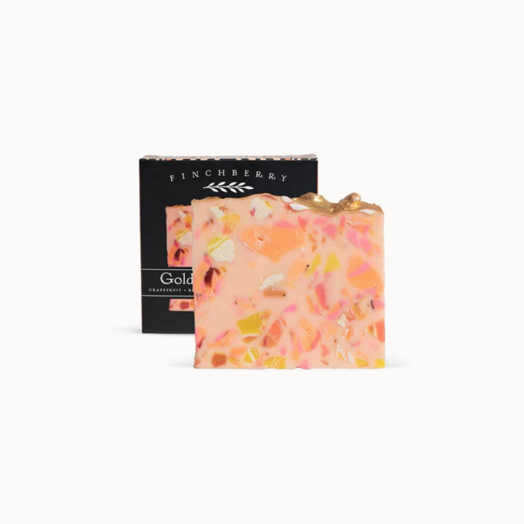 Colorful soap bar with visible ingredients next to a black Finchberry box on a white background
