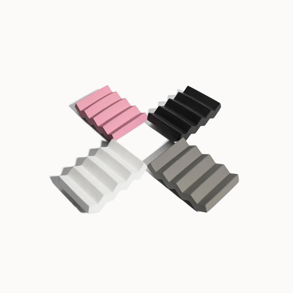Four wedge-shaped blocks in pink, black, white, and gray on a white background