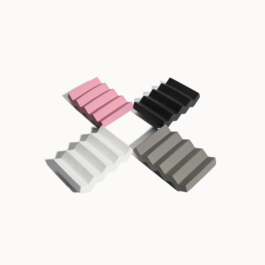 Four wedge-shaped blocks in pink, black, white, and gray on a white background