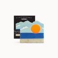Decorative soap with mountain and sun design in front of a Finchberry branded box.
