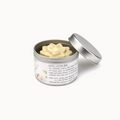 Metal container with white flower-shaped lotion bar on a white background