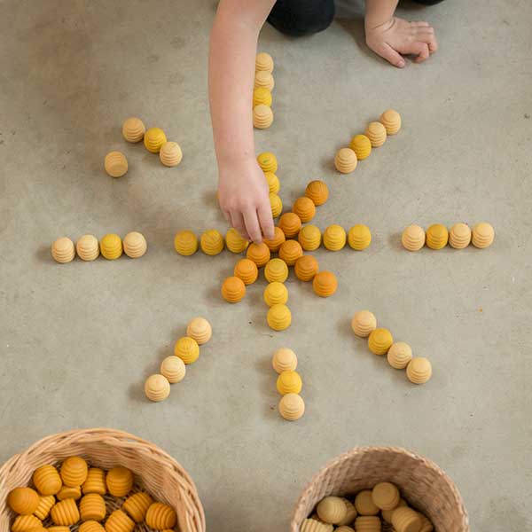 Yellow wooden toys on floor being played with by a child
