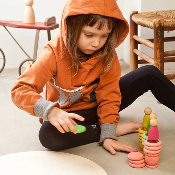 Child playing with colorful wooden toys on a light-colored floor.