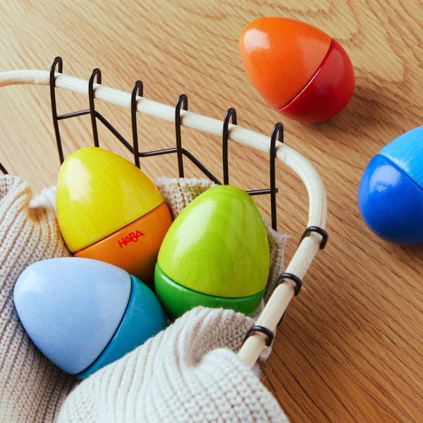 Colorful wooden eggs with HABA logo on a wooden surface