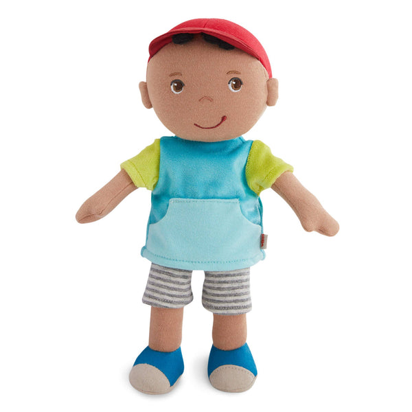 Plush toy doll with a red cap, blue shirt, green sleeves, gray shorts, and blue socks on a white background