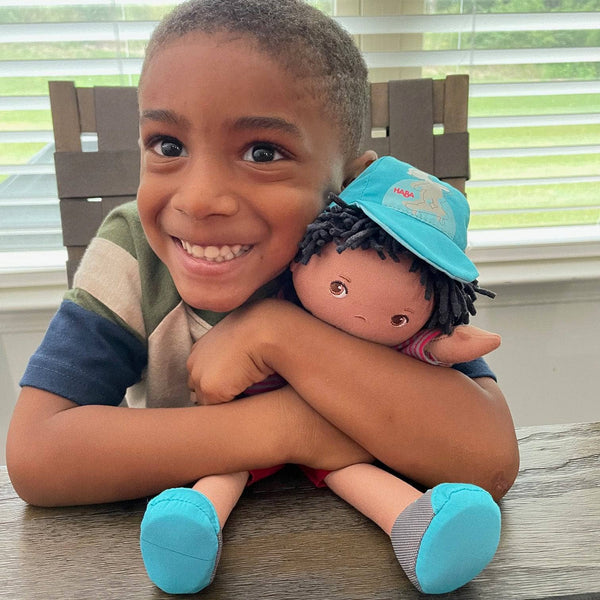 Child hugging a doll with a blue cap in a home setting