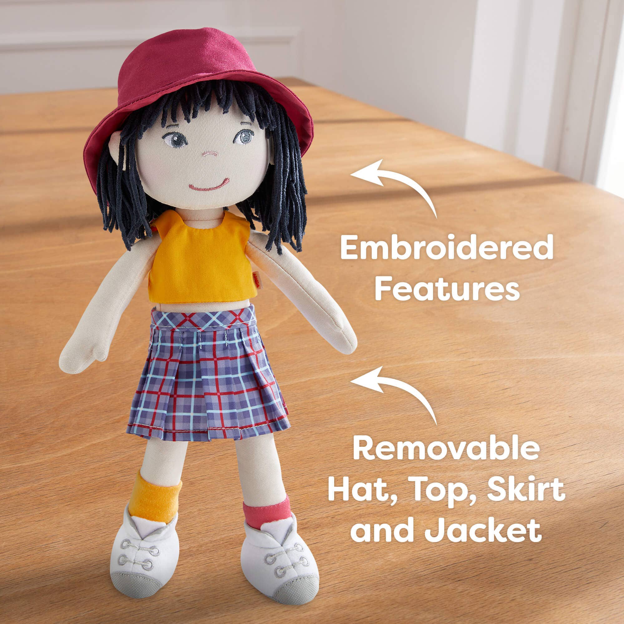 Doll with embroidered features and removable clothing on a wooden surface