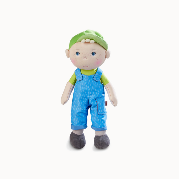 Stuffed toy doll with a green hat and blue overalls on a white background