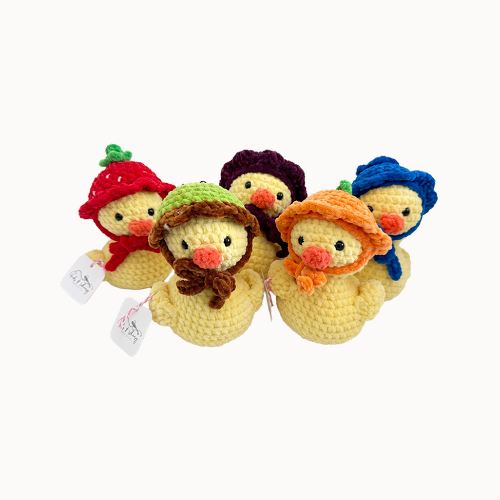 Stack of colorful crochet duck toys on a white background
