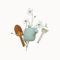 Decorative set with a small green teapot, brown shovel, and white flowers on a light background