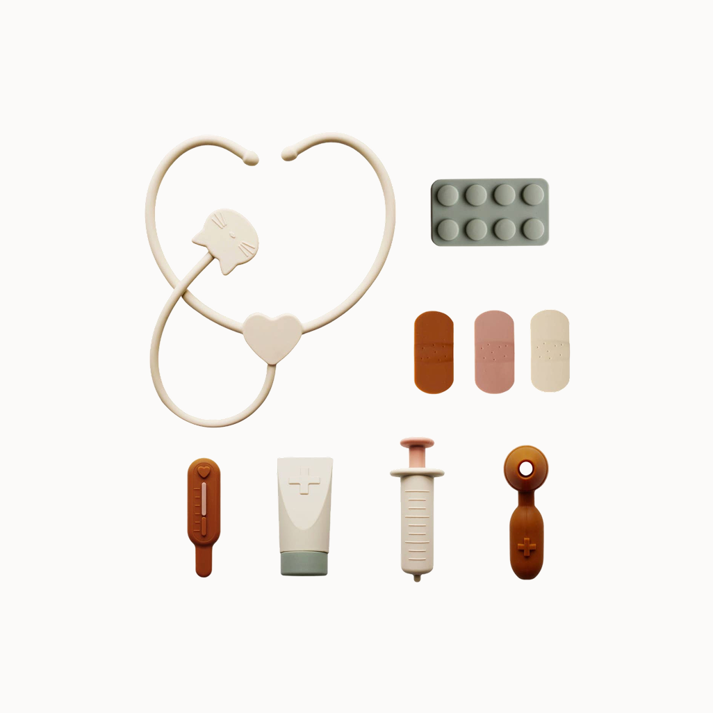 Collection of medical-themed toys including a stethoscope, syringe, and various other items on a white background.