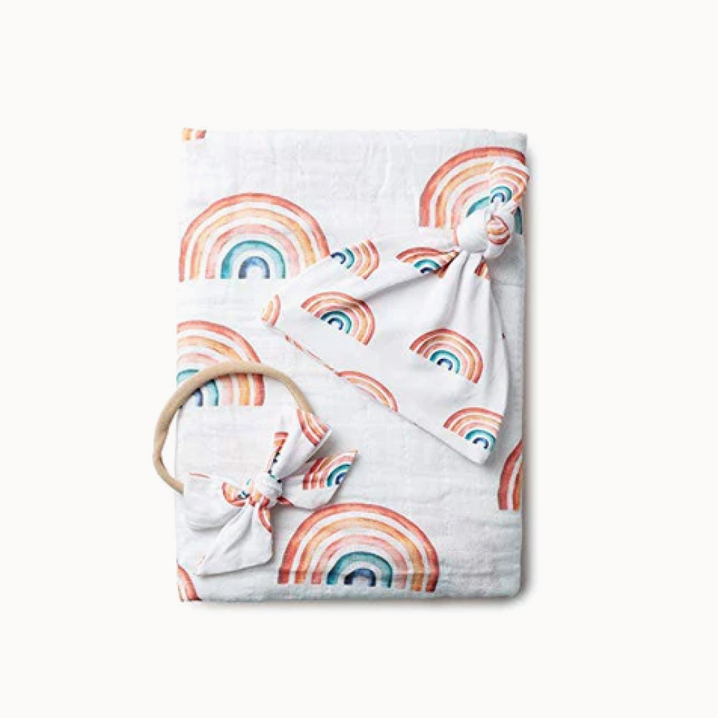 Baby blanket with rainbow pattern and teething ring on a white background