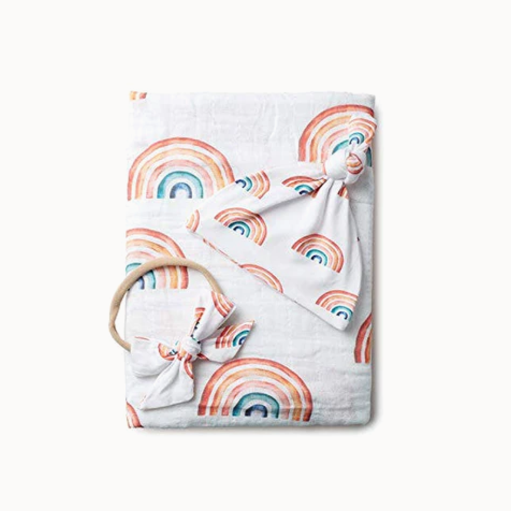 Baby blanket with rainbow pattern and teething ring on a white background