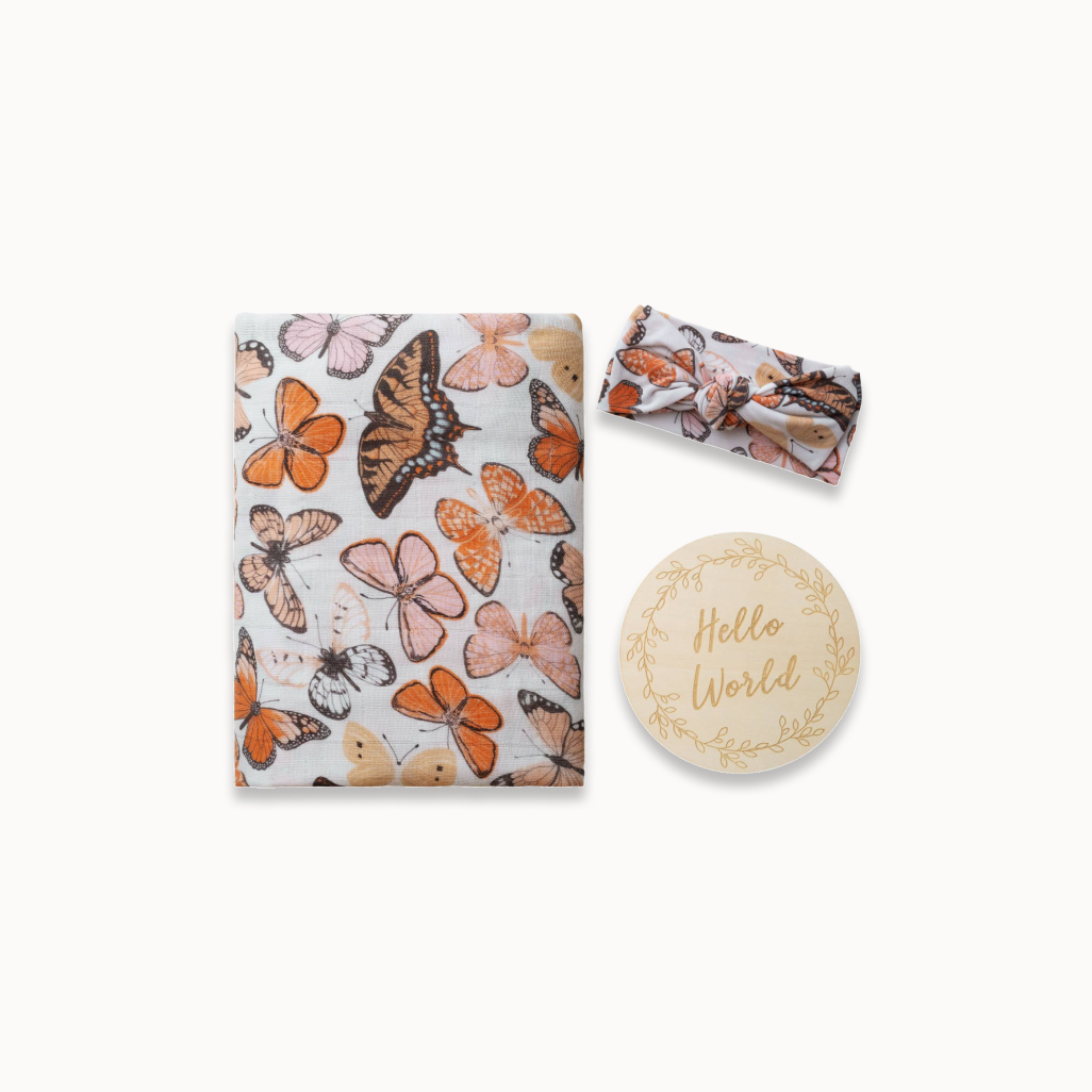 Butterfly-patterned baby blanket, headband, and 'Hello World' wooden disc on a white background