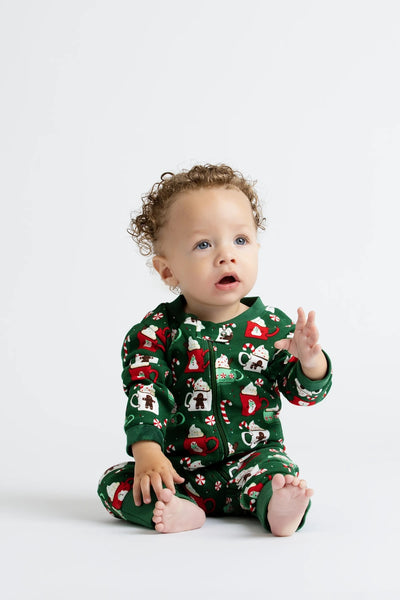 Baby wearing a green Christmas-themed onesie on a white background