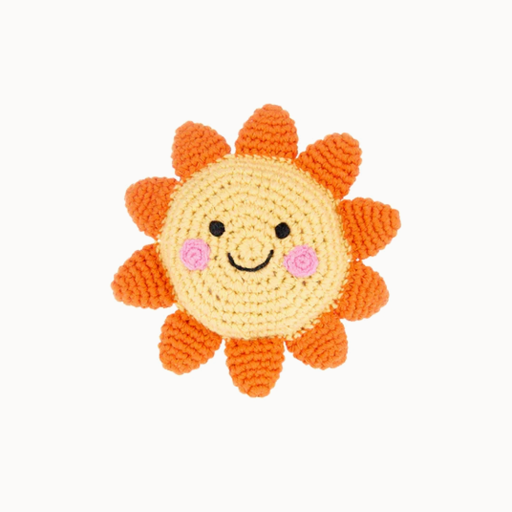 Crocheted sun-shaped toy with a smiling face on a white background