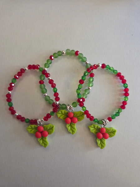 Beaded bracelet with green and red beads and leaf decorations on a light gray background