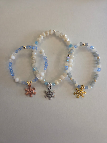 Two beaded bracelets with snowflake charms on a light gray background