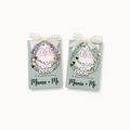 Two 'Mama + Me' beaded bracelets on cards with ribbons against a white background.