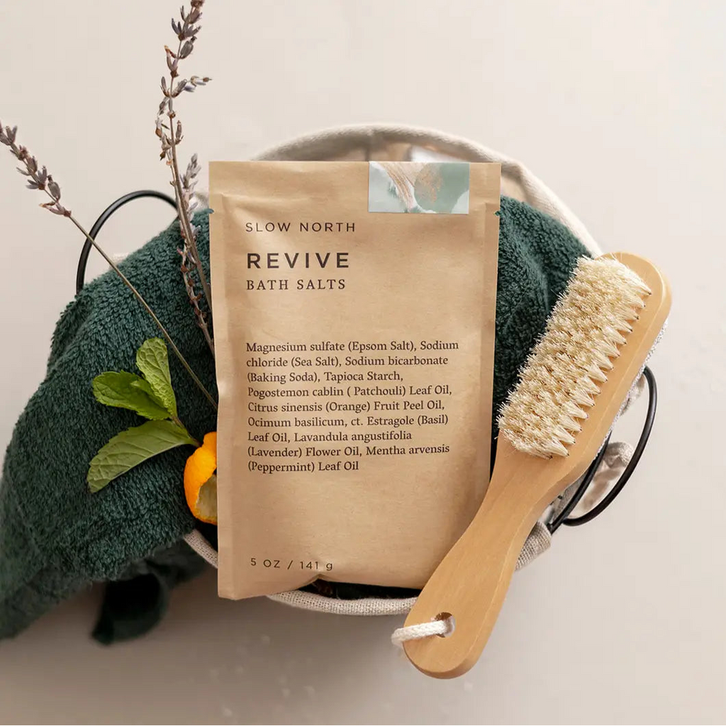 Bath salts package with a wooden brush and towel on a neutral background