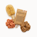 Bath salts package with a loofah, scrubber, and scrunchie on a white background