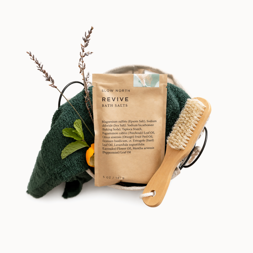 Bath salts package with a wooden brush and towel on a white background