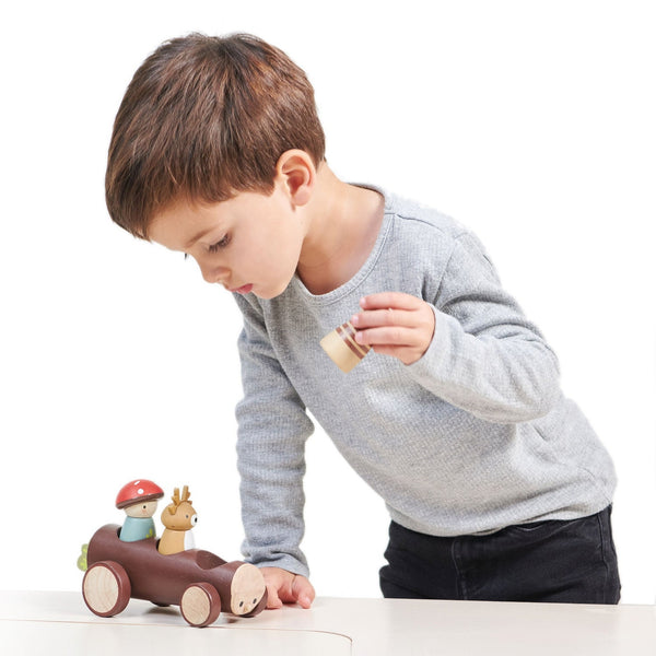 Child playing with wooden toy cars on a white background