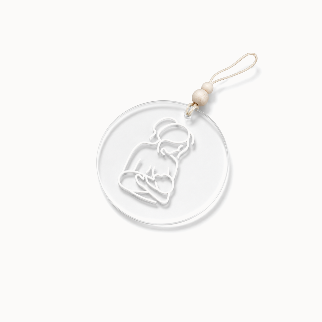 Clear ornament with white outline of illustration of a breastfeeding mother