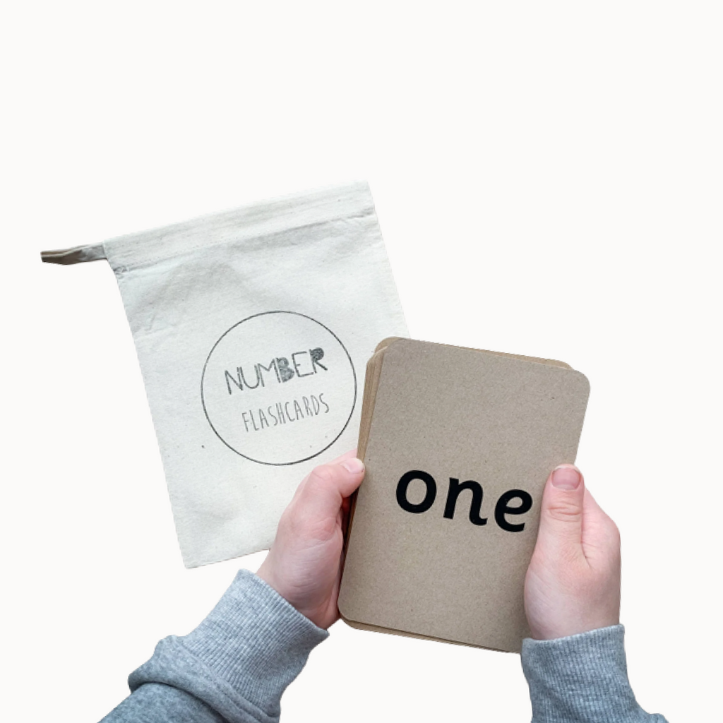 Kid's hands holding brown flashcards that says "one" and "Number flashcards" pouch in the back