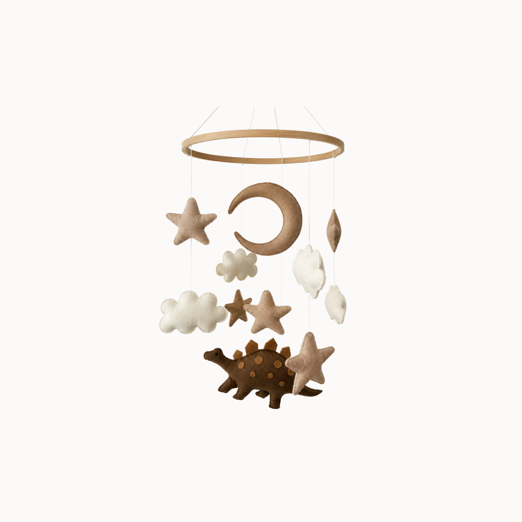 Brown and white nursery mobile with stars, cloud, moon, and dinosaur