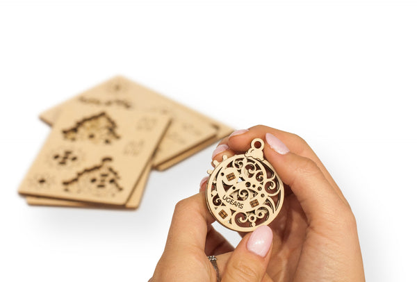 Hand holding wooden holiday ornament on white background 