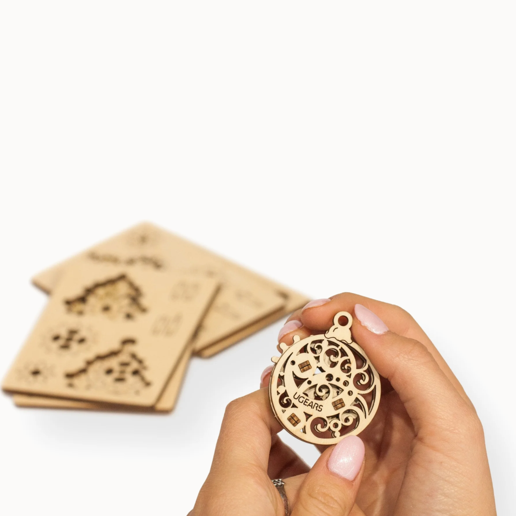 Hand holding wooden holiday ornament on white background 