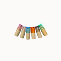 Six small cylindrical cosmetic tubes arranged in a curved row on a plain white background. The tubes have beige bottoms and translucent tops in pink, clear, blue, orange, gray, and green, with colored cream or gel visible inside.