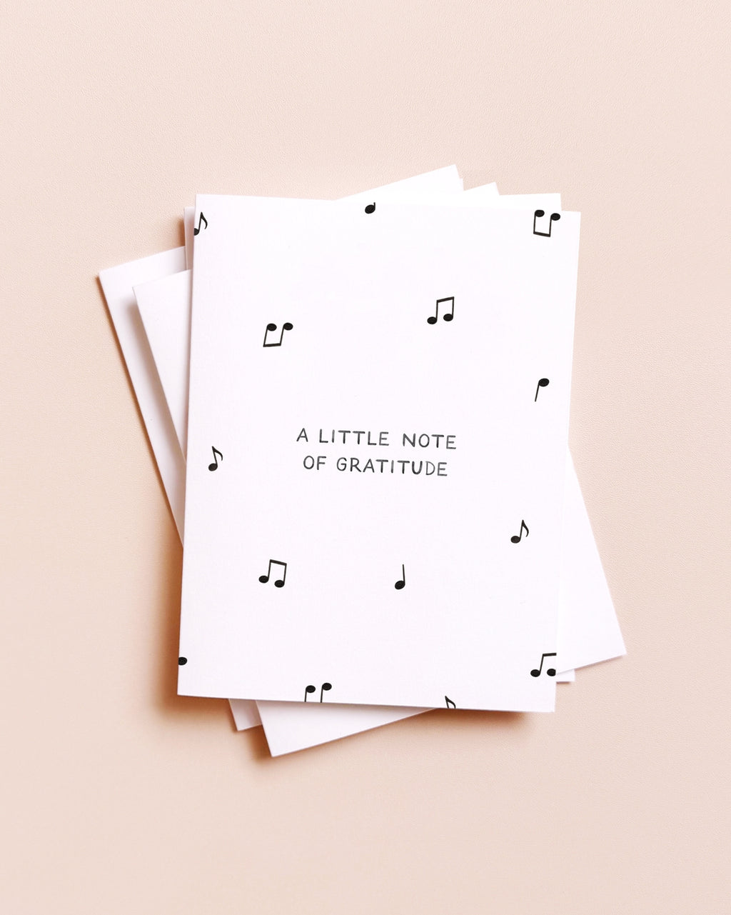 Stack of greeting cards with musical notes and 'A Little Note of Gratitude' text on a beige background