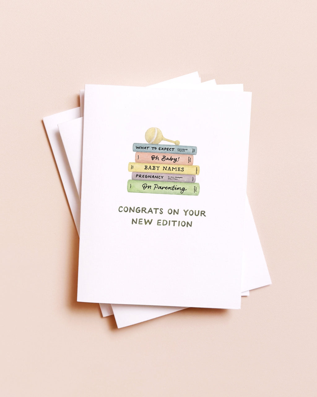 Stack of greeting cards with a baby shower theme on a beige background