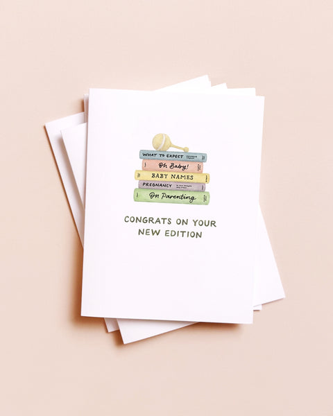 Stack of greeting cards with a baby shower theme on a beige background