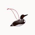 A loon ornament with a red hanging string, featuring black, white, and red details, set against a plain off-white background.