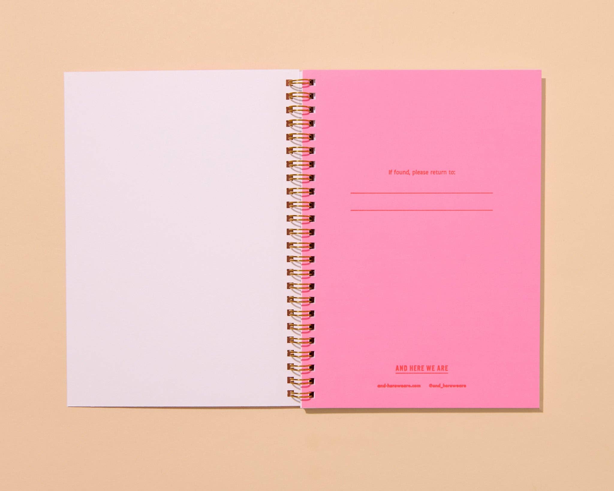 Pink spiral-bound notebook with white pages on a beige background