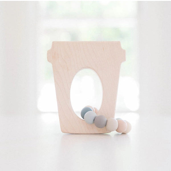Coffee cup teether toy on table with window background