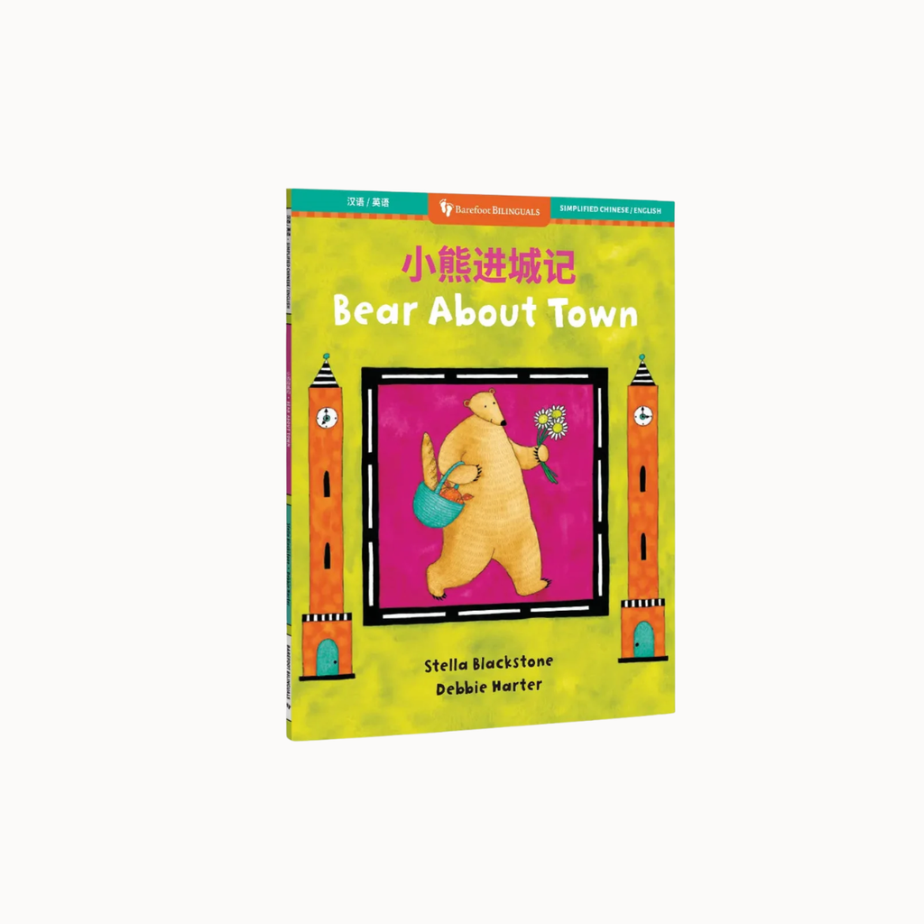 Children's book titled "Bear About Town" with Chinese text at the top, shown standing upright on a plain light gray background. The cover is predominantly yellow-green with a central illustration of a bear in a pink square, flanked by two orange towers.
